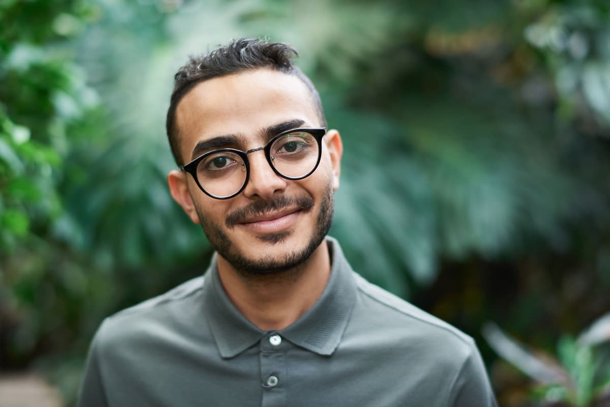 A young man in glasses stands outside