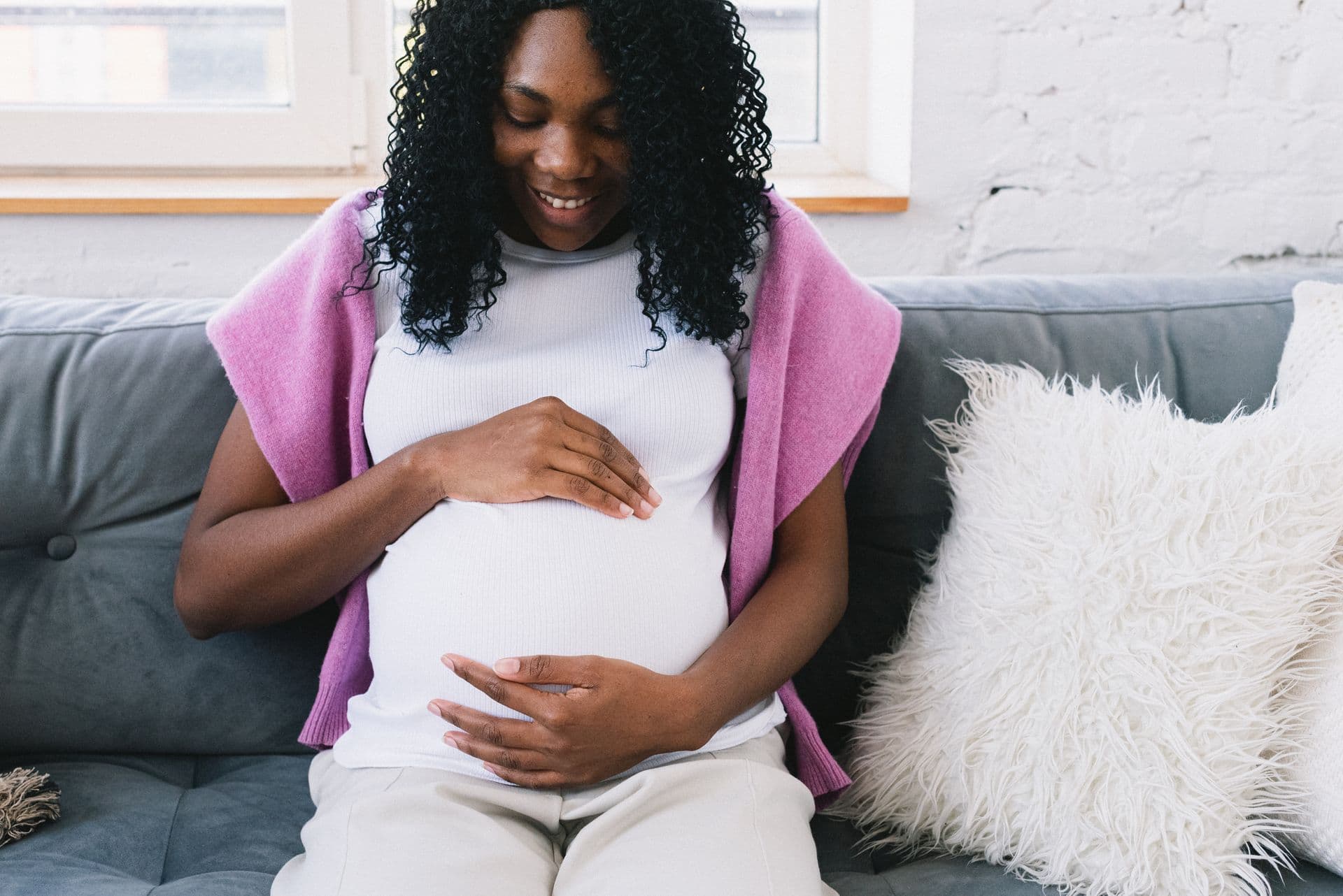A woman holds her hands over her pregnancy bump